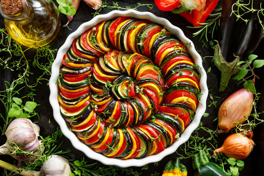Vegan french tian in a casserole dish on the black background, top view. 
