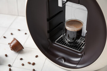 Modern capsule coffee maker with cup of espresso and beans on white table