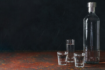 Bottle and glasses of vodka on table - obrazy, fototapety, plakaty