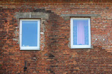 Two simple plastic windows in an old brick house. Modern technologies and ancient buildings