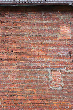A vertical photo of an old brick wall with a bricked up window. Ancient structure in the historic district of the city