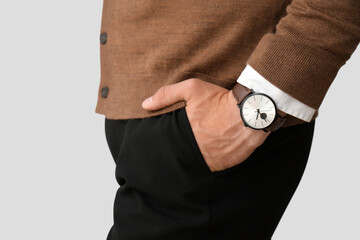 Stylish young man with wristwatch on grey background, closeup