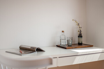 Indoor home office with table, magazine, glass, decorative plant, and water bottle