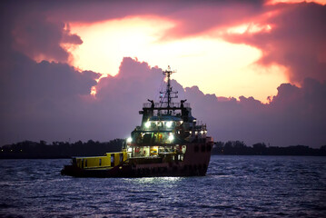 Cargo ship on the sea arriving to the harbor by night
