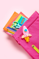 Backpack with rocket made of plasticine and stationery on pink background