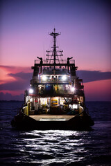 Cargo ship on the sea arriving to the harbor by night
