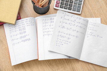 Open copybooks with math formulas on wooden table