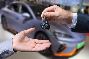 Auto business, car sale, transportation, people and ownership concept - close up of car salesman giving key to new owner or customer over auto show background.