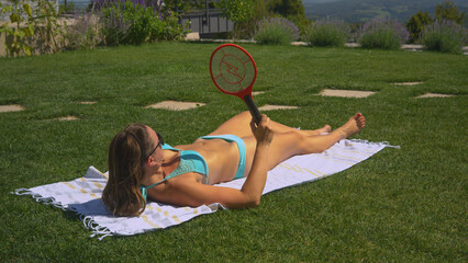 CLOSE UP: Annoying insects attack a young lady who tries to enjoy sunbathing