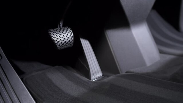 Brake and accelerator pedal with dark mats in the interior of a new car.