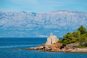 Fototapeta na wymiar Small place of worship on picturesque and rugged seashore on island of Hvar
