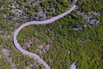 AERIAL TOP DOWN: Curvy asphalt road leading through rugged Adriatic landscape