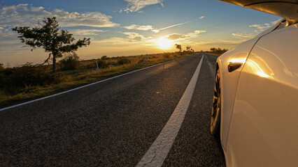 LENS FLARE: Car travelling in golden sunlight through bushy Adriatic landscape