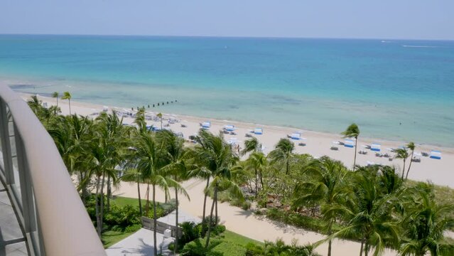 Captivating view from terrace of high-rise apartments in splendid resort in Miami. Tropical beach with exotic palm trees, crystal clear water of Atlantic ocean and white sand