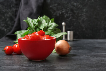 Bowl of canned tomatoes and onion on dark background