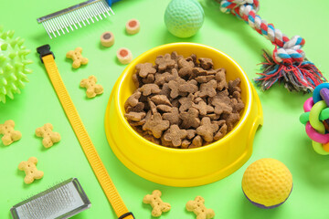 Composition with different pet care accessories and dry food on green background