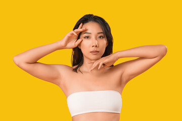 Fototapeta premium Beautiful young Asian woman with healthy skin on yellow background
