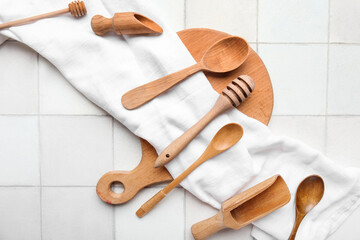 Composition with wooden kitchen utensils and napkin on light tile background