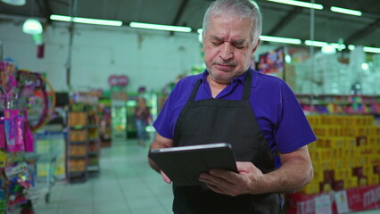 Frustrated Business owner of Supermarket holding tablet inspecting inventory struggling through hard times. Manager of Grocery store feeling stress and anxiety