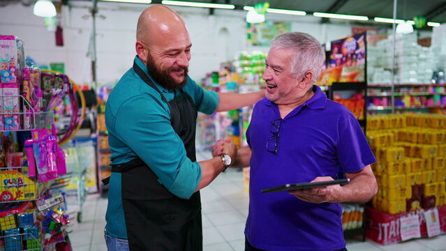 Senior manager giving high-five to male employee at supermarket. Boss congratulating staff for good job at grocery store business