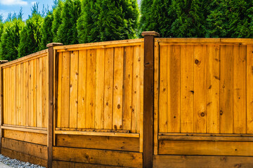 Beautiful new wooden fence around the house. Wooden fence with trees around. Solid Cedar fence.