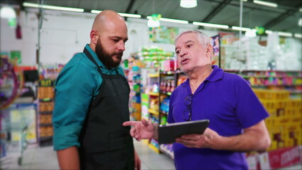 Senior manager of supermarket reproving employee, business boss reprimanding staff at grocery store holding tablet, showing lack of inventory