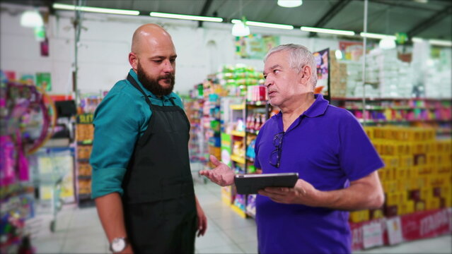 Senior manager of supermarket reproving employee, business boss reprimanding staff at grocery store holding tablet, showing lack of inventory