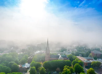 Fotobehang Church of Saint Marie in haze in Palanga, Lithuania. Aerial view on a foggy day © Audrius