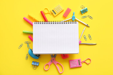 Composition with blank notebook and school stationery on yellow background