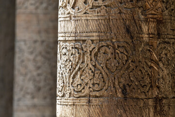 Wooden carved columns in the Juma Mosque. Famouse mosque of 10th century. Close up fragment, selected focus. Khiva, Uzbekistan