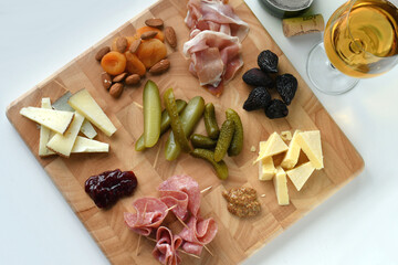 Cheese & charcuterie board with pickles, mustard, dried fruit, nuts, fruit spread with wine