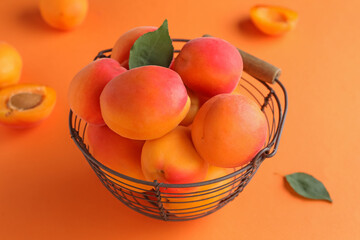 Basket with sweet apricots on orange background