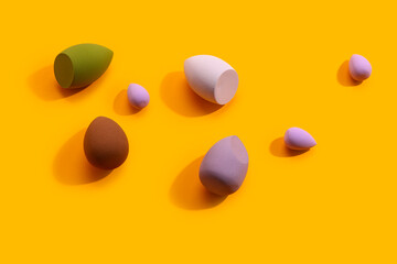Different makeup sponges on orange background