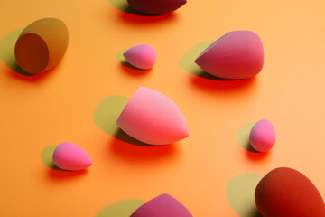 Different makeup sponges on orange background