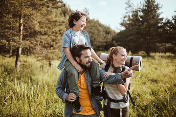 Young family hiking in the forest and crossing a creek together