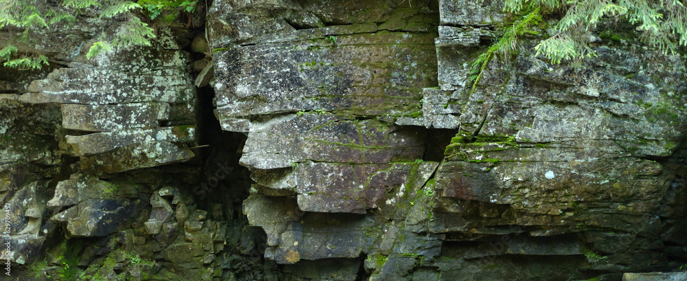 Poster rock formation in a forest made up of large, jagged rocks that are stacked on top of each other cove