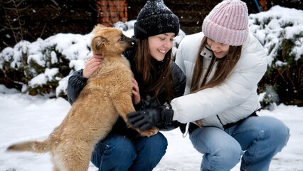 Two happy girls with dog having fun in snow at house backyard. Kids with animals, games with pets.