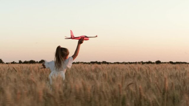 little child girl kid daughter runs through wheat field with toy plane her hand, happy family dream fly, agricultural farm, sunset field, sleep, becomes pilot plane children dream, fun fantasy, travel