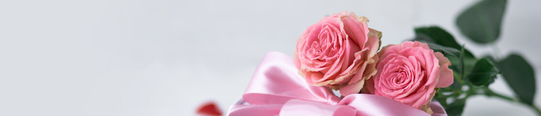 Beautiful surprise greeting for saint Valentine's or Women's Day, birthday or Anniversary for beloved. Fresh pink roses, gift box with sweets. White background. Holiday atmosphere. Banner copy space