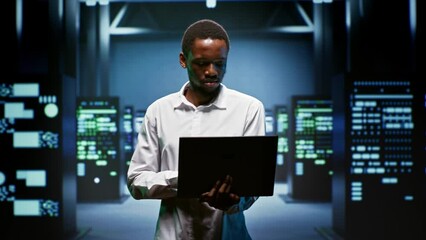 Portrait of smiling admin using laptop to assess energy consumption across server rackmounts components. Professional making sure data center mainframes temperature sensors are running smoothly
