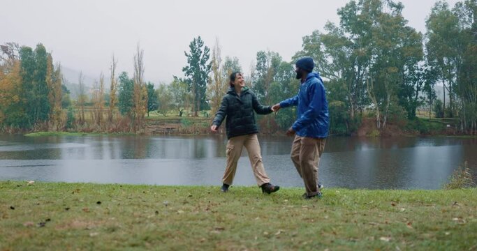 Couple, dance and happy date in countryside, park or camping in nature or forest for vacation, trip or fun adventure together. Men, outdoor and celebration of interracial love, relationship and rain