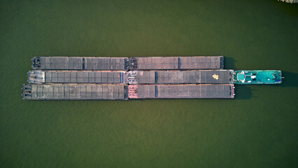 Aerial view of tugboat pushing barges up a river