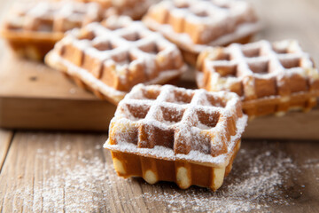 Fototapeta na wymiar set of square waffles, drizzled generously with delicate sprinkle of powdered sugar, beautifully arranged on rustic wooden tabletop