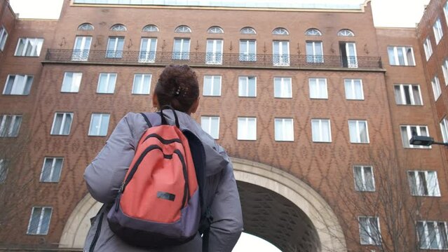 Lady by urban architecture with brick facades. A young lady traveler in urban city road with brick fasade during morning time.