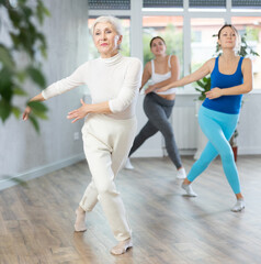 Obraz premium Positive women doing aerobics exercises in gym area during workout session