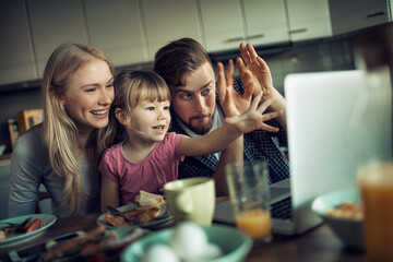Young family having breakfast in the morning and using a laptop