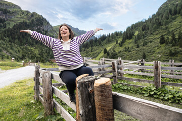 Fototapeta na wymiar Young woman sitting on wooden care and enjoying life, concept of inspiration, unity with nature, ecotourism, Austria
