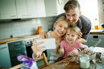 Young family taking a selfie while baking in the kitchen
