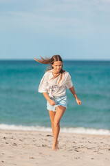 Adorable young girl enjoy tropical beach vacation. The girl on the seashore run and have fun