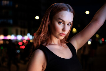 Plakat beautiful white woman with red hair in front of a city light in the evening